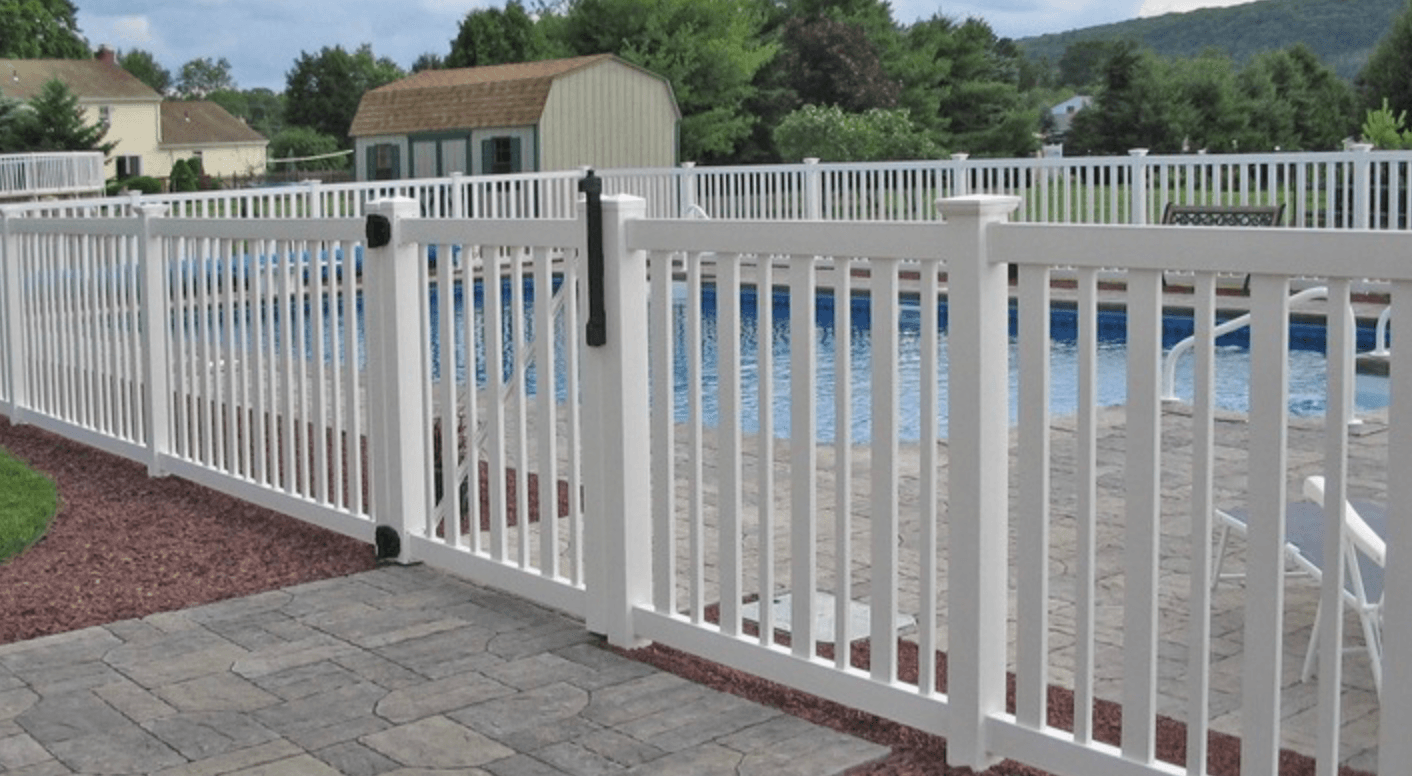 A white slatted vinyl fence around a pool deck.